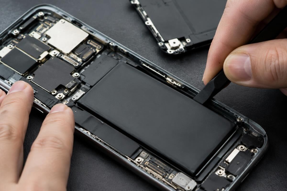 Åbnet smartphone hvor et nyt batteri monteres med præcisionsværktøj